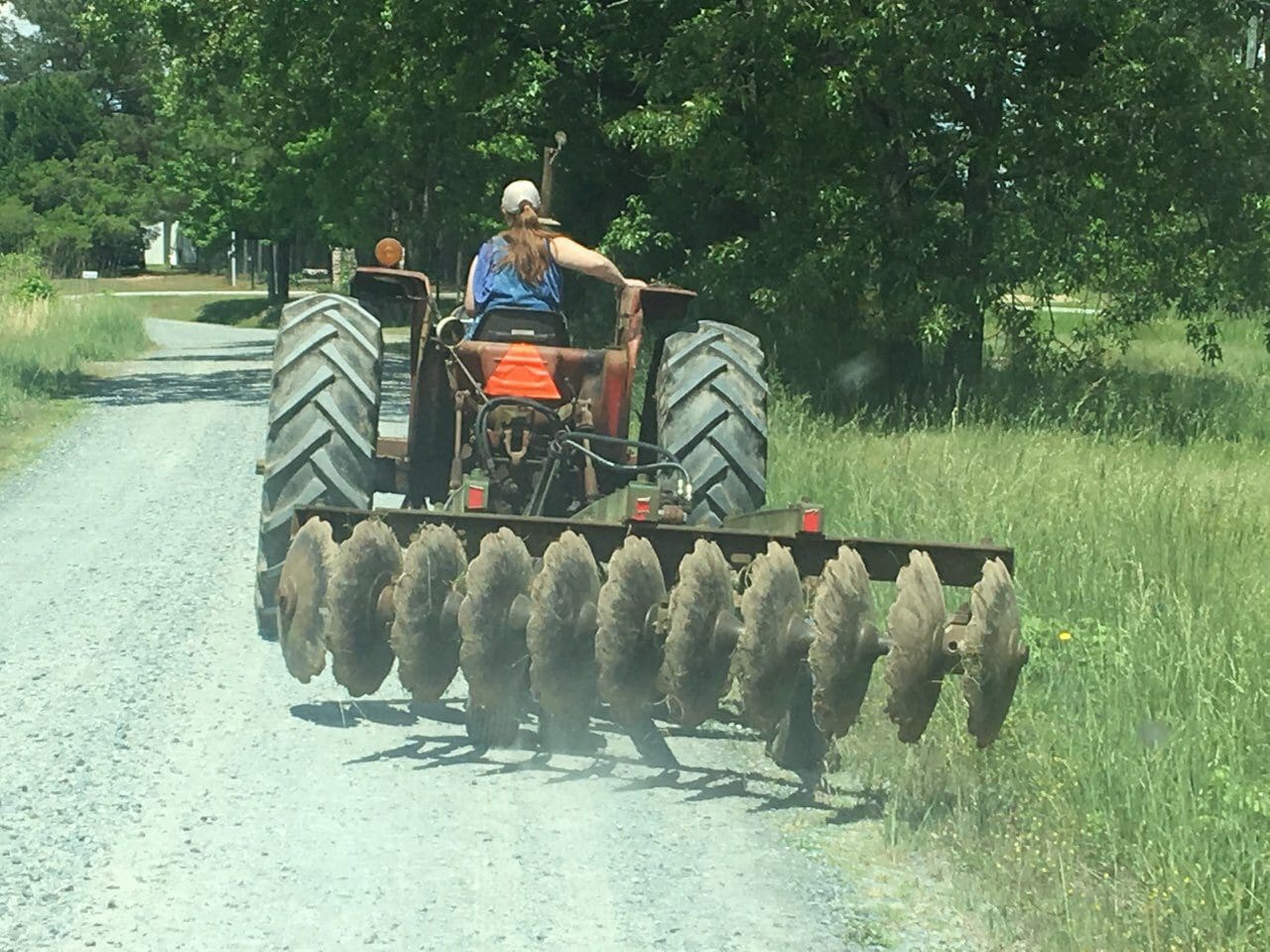 A man riding on the back of an orange tractor.